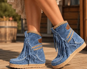 May include: Blue suede ankle boots featuring long fringe detailing, a scalloped beige trim along the collar, and a woven jute platform sole. The boots are accented with white whipstitch detailing along the toe and sides, and a small brown patch.