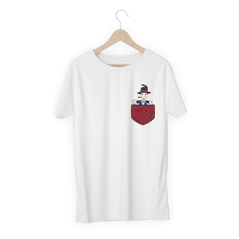 Pu&ograve; includere: T-shirt bianca con tasca rossa raffigurante un personaggio dei cartoni animati con cappello nero e pipa. Il personaggio indossa un papillon blu e un abito nero. La t-shirt &egrave; appesa a una gruccia di legno.