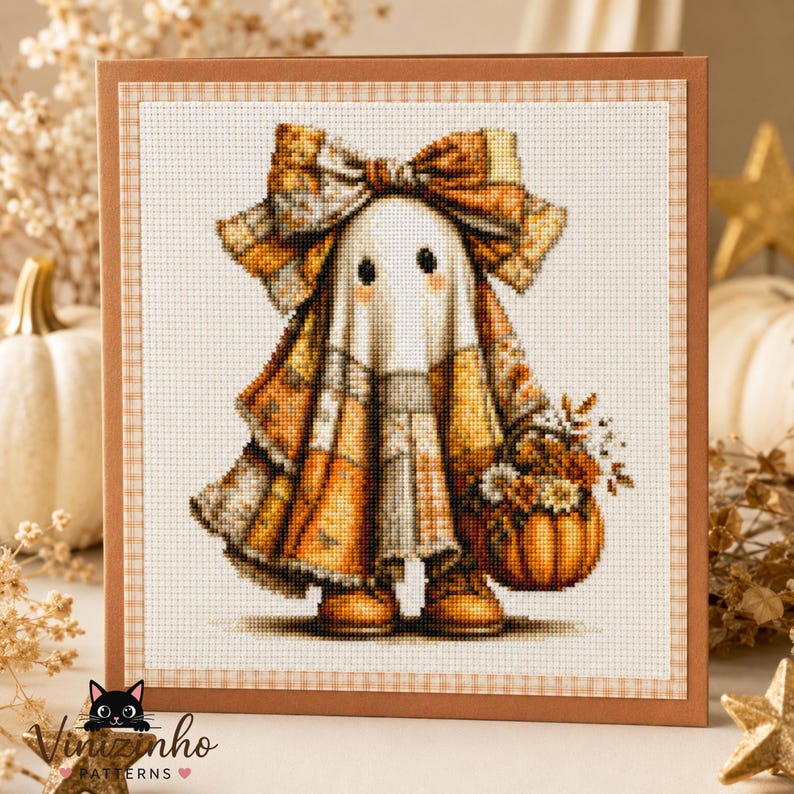 May include: A cross-stitch pattern card featuring a ghost character wearing a large plaid bow and a plaid cloak in shades of orange, brown, and cream. The ghost holds a small basket filled with autumn flowers and a pumpkin, set against a grid background.