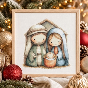 May include: A framed cross-stitch embroidery depicting a nativity scene with two figures standing behind a small infant in a manger. The figures wear muted green and blue robes, and the entire scene is rendered in a soft, pixelated style.