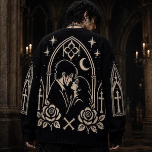 May include: Black sweater with a gothic design, depicting a couple embracing beneath a moon and stars. The sweater features cream-coloured gothic arches, crosses, roses, and a cross design. The person is wearing the sweater in a dark, gothic setting.