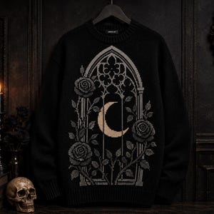 May include: A black long-sleeve knit sweater featuring a central graphic of a light-colored crescent moon framed within a tall, pointed gothic archway. The design includes detailed illustrations of climbing rose vines with leaves and blooming roses.