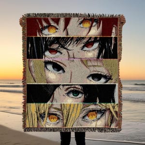 Peut inclure: Une couverture tissée avec un motif d'yeux de style anime de différentes couleurs, dont le rouge, le jaune et le vert. La couverture a une bordure à franges et est présentée sur une plage.