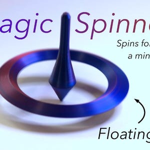 Op de afbeelding: Een donkerblauwe en paarse metalen tol met een puntige basis en een brede, platte ring. De tekst Magic Spinner, Spins for over a minute, en Floating! met een pijl die naar de ring wijst, zijn zichtbaar op de witte achtergrond.