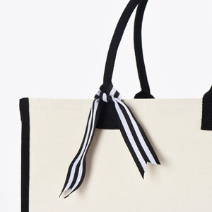 a white bag with a black and white striped bow