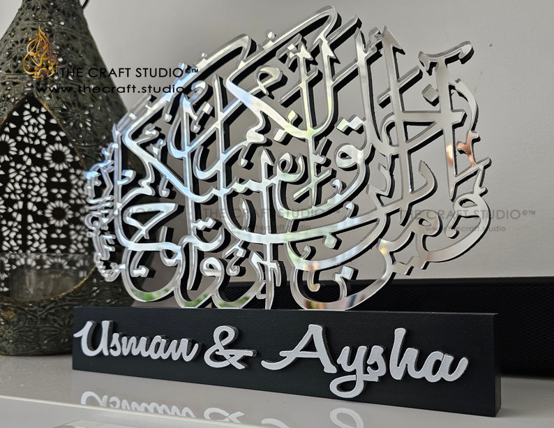 Op de afbeelding: Zilveren spiegelende acrylkalligrafiekunst met de namen Usman & Aysha op een zwarte basis.