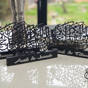 May include: Three black wooden plaques with Arabic calligraphy designs and personalized names. The names on the plaques are "Hussain", "Avel & Jannah", and "Trisal & Fatima".