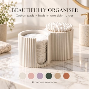 May include: A cream-coloured, ribbed, dual-compartment bathroom organiser holding a stack of white cotton pads and a cluster of cotton swabs. The text reads: BEAUTIFULLY ORGANISED, Cotton pads + buds in one tidy holder, 6 colours available.