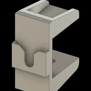 May include: A light gray, 3D-rendered bracket with a U-shaped design. The bracket features a rectangular base, a vertical support with a curved cutout, and a top section with a recessed area. A threaded hole is visible on the side.