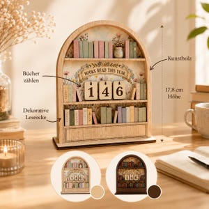 Può includere: Uno scaffale ad arco in legno con la scritta BOOKS READ THIS YEAR e tre blocchi rotanti che mostrano il numero 146. L'oggetto è alto 17,8 cm e presenta dorsi di libri in miniatura colorati su due ripiani con uno sfondo floreale.