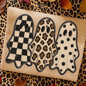 May include: A rectangular sheet of light brown paper featuring three ghost illustrations. The first ghost has a black and white checkerboard pattern, the second has a brown and black leopard print, and the third has black polka dots.