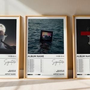 May include: Three vertical posters in light wood frames featuring album art designs. Each print displays a central image, the text ALBUM NAME, a tracklist numbered 1 through 19, a signature graphic, and the text RELEASED ON MARCH 24 2016 ARTIST NAME.