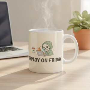 May include: A white ceramic mug featuring a graphic of a skeleton in a green hoodie typing on a laptop with flames behind it and a calendar marked FRI. The text DEPLOY ON FRIDAY is printed in black below the illustration on the front of the mug.