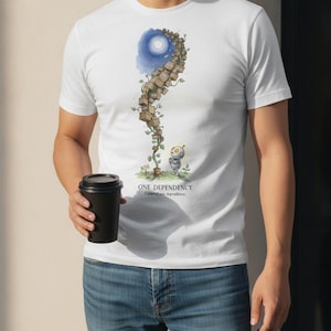 Puede incluir: Una camiseta blanca con una ilustración gráfica de un pequeño robot de pie junto a una alta enredadera sinuosa hecha de cajas de madera apiladas que llegan hasta una luna azul. El texto "ONE DEPENDENCY" aparece bajo la ilustración.