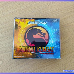 Peut inclure: Un boîtier de jeu vidéo Sega Mega-CD pour Mortal Kombat Psycho Red Edition. La couverture présente un logo de dragon noir central sur un fond divisé en jaune et bleu, avec le texte Sega Mega-CD, Mortal Kombat et Psycho Red Edition.