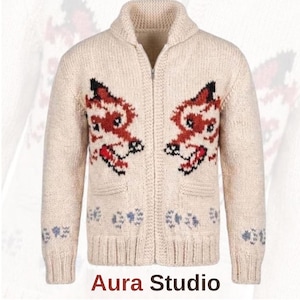 May include: A cream-coloured knit zip-up cardigan featuring a shawl collar and long sleeves. The front displays two symmetrical red and black fox head motifs above a row of small blue paw prints. The text Aura Studio is printed at the bottom.