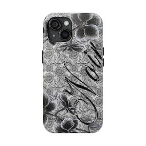 May include: A phone case featuring a black and white floral design with the name "Noir" in a cursive font. The case has a gray lace-like background with black orchid flowers.