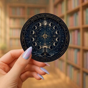 May include: A round sticker featuring a detailed illustration of the moon phases, a lighthouse, and a compass rose. The sticker has a dark blue background with gold accents and the text "MOON PHASE OBSERVATORY".