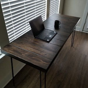 May include: A dark wood desk with hairpin legs and a laptop computer on the surface. A coffee mug is also on the desk.