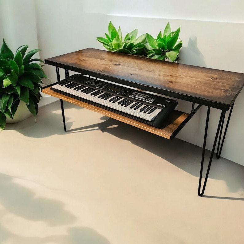 May include: A wooden table with black hairpin legs and a shelf underneath. A black keyboard is sitting on the shelf. The table is made of wood with a natural finish.