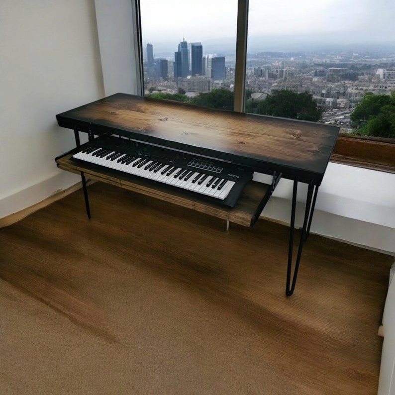 May include: A wooden desk with a black keyboard and a city skyline view out the window. The desk has black hairpin legs.