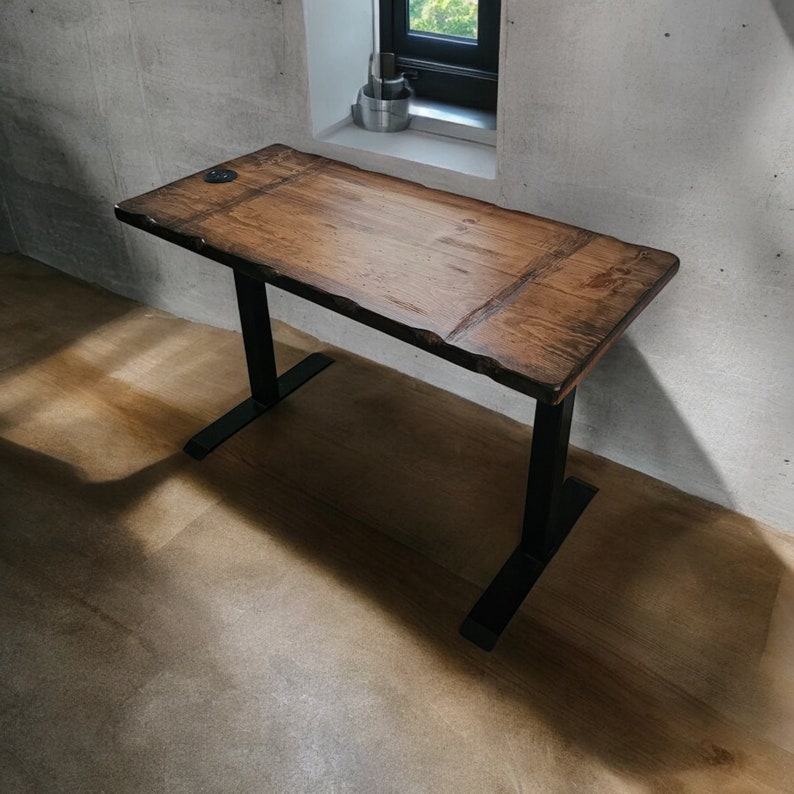 May include: A wooden desk with a live edge top and black metal legs. The desk has a natural wood finish and is supported by a metal frame.