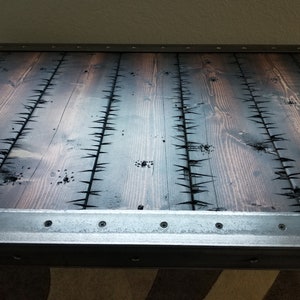 May include: A rustic wooden table top with a dark stain and a metal trim around the edge. The wood has a unique design with small, sharp points protruding from the surface.