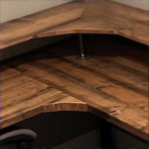 May include: Close-up of a corner wooden countertop with a natural wood grain pattern. The countertop has a light brown color and is constructed with multiple wooden planks. A metal support is visible.