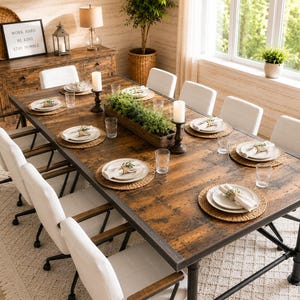 May include: A rectangular dining table with a distressed brown wood top and black metal pipe legs, surrounded by eight white upholstered chairs. The table is set with woven placemats, white plates, napkins, glassware, and a central wooden planter.