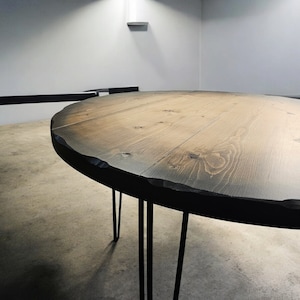 May include: A round wooden table with a dark brown stain and a live edge. The table has black hairpin legs.