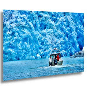 May include: A motorboat sails on blue water, set against a backdrop of a large, textured blue glacier. The boat features a cabin and fishing rod holders. A person in a red jacket is visible. The image evokes a sense of adventure and the beauty of nature.