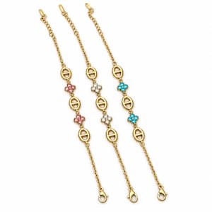 Peut inclure: Trois bracelets à chaîne dorée composés de maillons ovales alternés et de motifs floraux à quatre pétales. Le premier bracelet présente des pierres roses, le deuxième des pierres blanches transparentes et le troisième des pierres bleu vif.