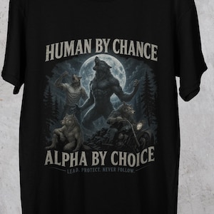 Puede incluir: Camiseta negra con un diseño de hombres lobo bajo la luna llena. El diseño incluye el texto "HUMAN BY CHANCE" encima de la imagen y "ALPHA BY CHOICE" debajo, con el lema "LEAD. PROTECT. NEVER FOLLOW."