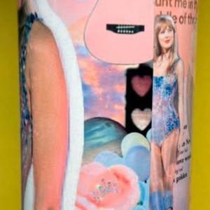 May include: A cylindrical tumbler featuring a collage of pink and blue imagery, including a guitar, heart-shaped sunglasses, a playing card, and text such as daylight, paper rings, and girl, you need to calm the f down, with photographic portraits.