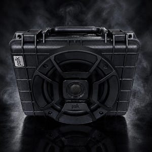 May include: A black portable speaker housed in a rugged, rectangular, grid-patterned case with a top handle. The front features a circular speaker grille with the Polk logo centered at the bottom and on the left side, surrounded by wispy smoke.