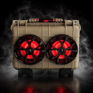May include: A tan, rectangular, hard-shell protective case converted into a portable speaker system. It features two circular black speaker grilles with vibrant red LED lighting, a top carrying handle, and two black support feet at the base.