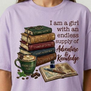 May include: A light purple t-shirt featuring a graphic of a stack of five books, a green mug labeled Knowledge Fuel, an open book, and an inkwell with a pen. The text reads: I am a girl with an endless supply of Adventure & Knowledge.