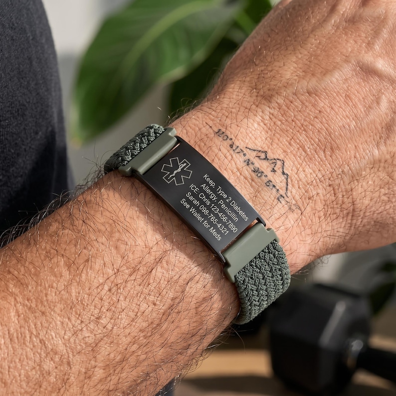 May include: A medical alert bracelet featuring a black rectangular metal plate with a white Star of Life symbol and engraved text: Keep, Type 2 Diabetes, Allergy, Penicillin, ICE: Chris 123-456-7890, Sarah 098-765-4321, See Wallet for Meds. Olive green braided band.