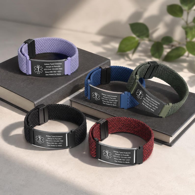 May include: Five medical alert bracelets with woven elastic bands in lavender, blue, olive green, black, and maroon. Each features a rectangular metal plate with a Star of Life emblem and engraved text including Kelsey, Type 2 Diabetes, and emergency contacts.