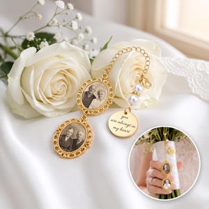 May include: A gold-toned metal charm featuring two oval frames with black and white photographs of people, connected by a chain with two white pearls. A round gold disc is attached, engraved with the text, you are always in my heart.