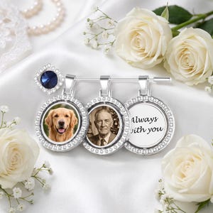 May include: A silver-toned brooch featuring three circular pendants framed with clear crystals. The pendants display a golden retriever, a portrait of an elderly man, and the text Always with you. A dark blue crystal accent sits at the top left.