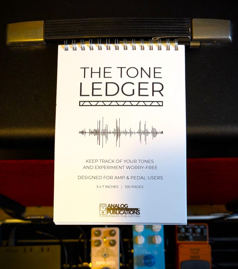 May include: A white spiral-bound notebook titled "THE TONE LEDGER" with black text and a sound wave graphic. The notebook is 5x7 inches and has 100 pages. It is designed for amp and pedal users.
