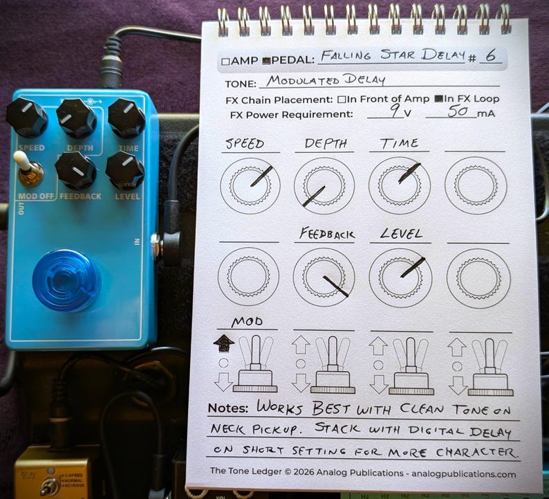 May include: A light blue guitar effects pedal with black knobs and a blue LED light. A notepad next to the pedal has handwritten notes about the pedal's settings, including "Falling Star Delay #6" and "Modulated Delay."
