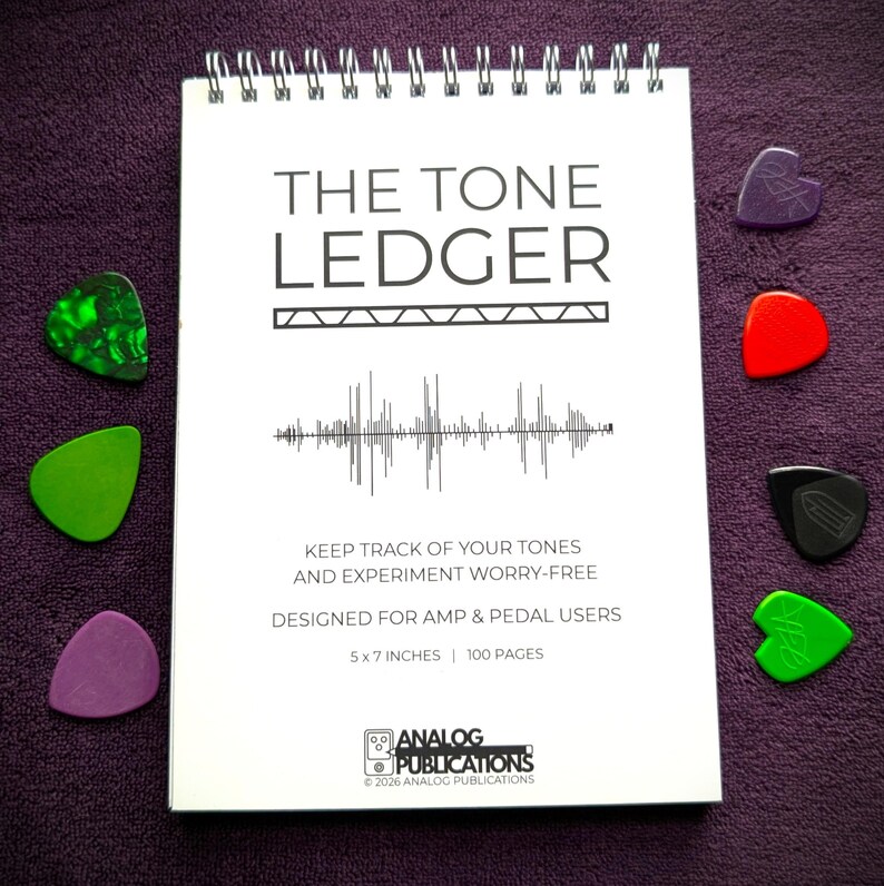 May include: A spiral-bound notebook titled "THE TONE LEDGER" with a sound wave graphic, designed for amp and pedal users. The notebook is 5 x 7 inches and has 100 pages. Six guitar picks in various colors surround the notebook on a purple surface.