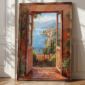 May include: A framed painting depicts an open window overlooking a coastal Italian village. The artwork features a terracotta-tiled balcony, open wooden doors, and a wrought-iron railing. The view includes sailboats on the blue sea and a distant village.