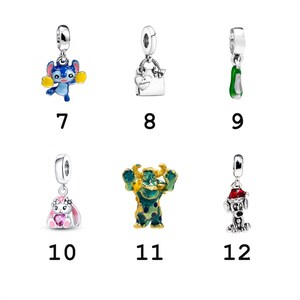 May include: A collection of six silver charms featuring a blue alien with yellow pom-poms, a shopping bag with a heart, a green shoe, a white rabbit with a pink heart, a green and blue monster, and a dog wearing a red Santa hat.