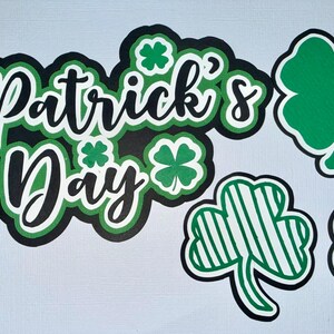 May include: A St. Patrick's Day design with the text "St. Patrick's Day" in black and white with green accents, and four-leaf clovers in green and white. Ideal for festive decorations and celebrations.