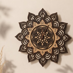May include: A decorative wooden wall clock with a mandala design. The clock features a layered, floral-like pattern in shades of brown and tan. The clock hands are visible, indicating the time. The clock is mounted on a neutral-coloured wall.