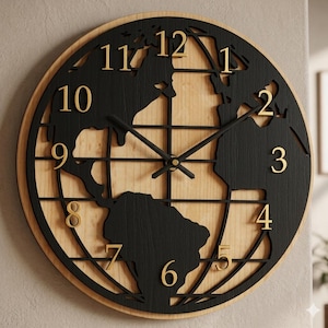 Puede incluir: Un reloj de pared redondo con un fondo de madera clara natural y una superposición negra con forma de mapa mundial. La esfera incluye números dorados del 1 al 12 y manecillas negras finas centradas sobre el diseño del mapa.