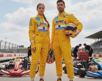 May include: Two individuals wearing bright yellow racing jumpsuits featuring blue Camel, Honda, Elf, and Nacional logos. The jumpsuits have long sleeves, high collars, and matching yellow racing boots. One person holds a multi-colored racing helmet.
